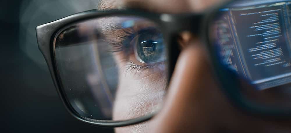 Close up of Man with computer data reflected in glasses, pondering why study fintech