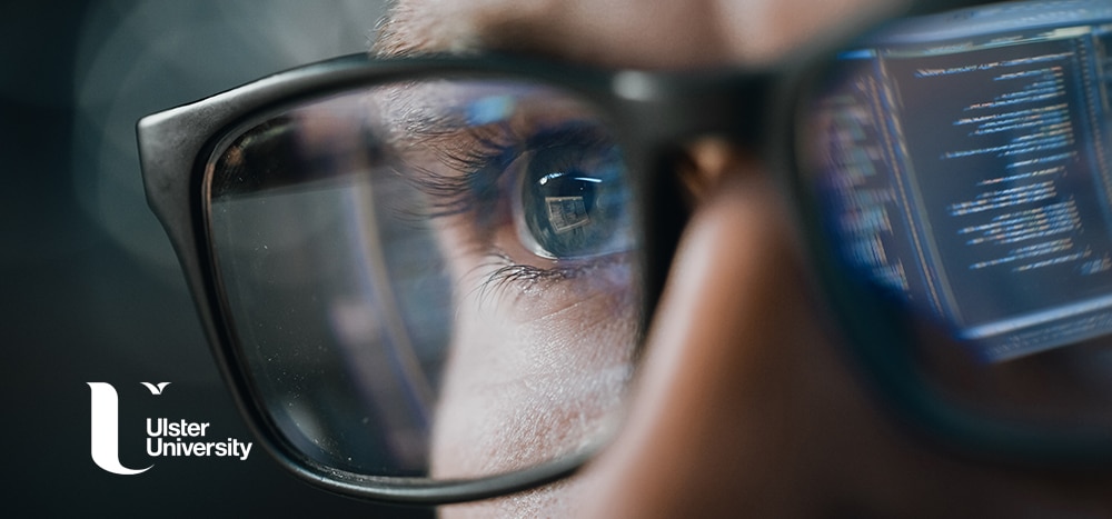Close up of Man with computer data reflected in glasses, pondering why study fintech at Ulster
