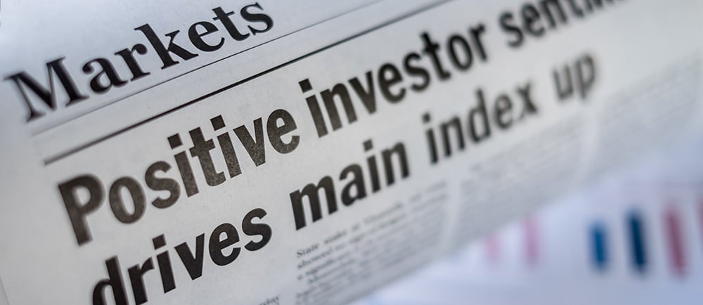 Newspaper headline reads ' positive investor sentiment drives main index up' - behavioural finance concept