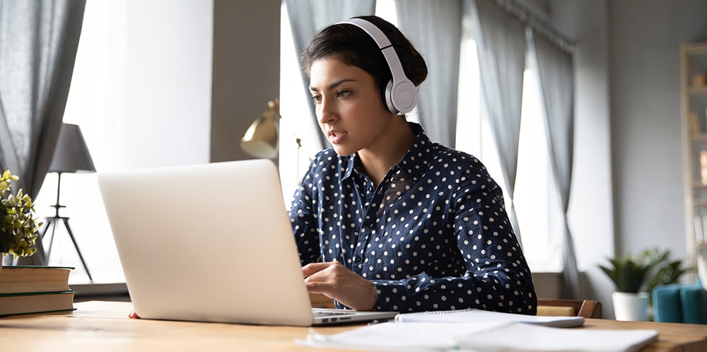 Young indian woman wearing headphones, looking for the best online fintech course